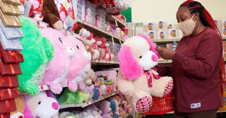 This photo shows a customer shopping in the seasonal items section of a Combo Store, holding a stuffed animal.
